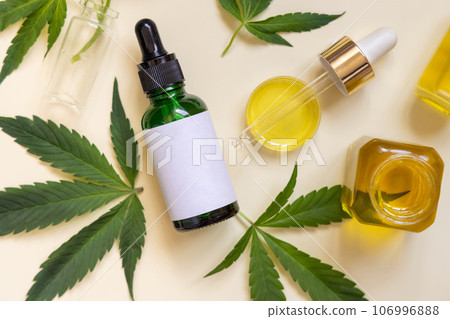 Pipette and dropper bottle near green cannabis leaves top view on beige, CBD cosmetics Pipette and dropper bottle near green cannabis leaves top view on beige, CBD cosmetics 106996888