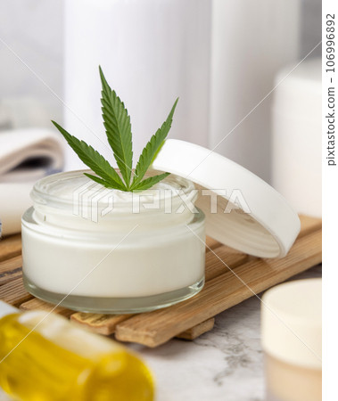 Opened cream jar with green cannabis leaves close up, organic natural CBD cosmetic Opened cream jar with green cannabis leaves close up, organic natural CBD cosmetic 106996892