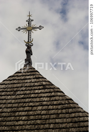 old wooden church against the blue sky in Ukraine, wooden roof with a cross old wooden church against the blue sky in Ukraine, wooden roof with a cross 106997719