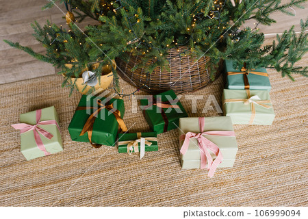 Variety of gift boxes with ribbons lie under the Christmas tree in the living room Variety of gift boxes with ribbons lie under the Christmas tree in the living room 106999094