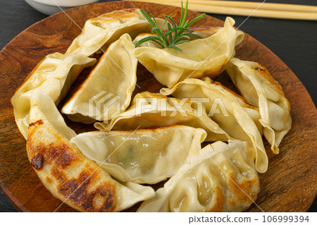 Gyoza Chinese Dumplings on Wood Plate, Fried Vegetable Jiaozi Macro, Chicken Momo Pile, Asian Gyoza Closeup 106999394