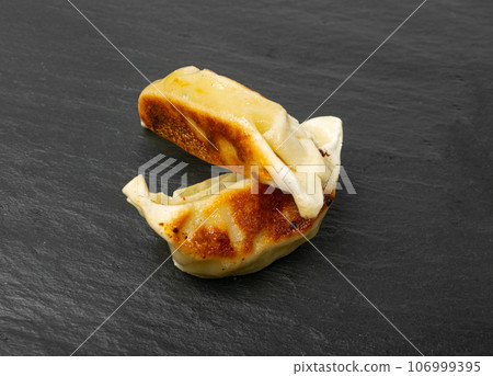 Gyoza Chinese Dumplings, Fried Vegetable Jiaozi, Chicken Momo Pile, Asian Gyoza Group on Black Stone Plate 106999395