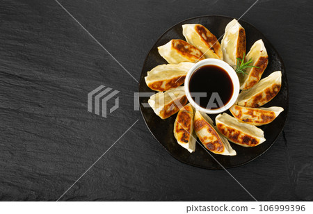 Gyoza Chinese Dumplings on Black Plate, Fried Vegetable Jiaozi, Chicken Momo Pile, Asian Gyoza Group 106999396