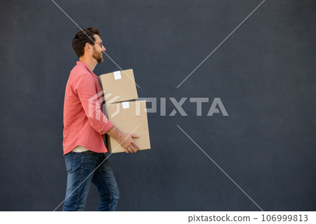 Dark-haired young man in eyeglasses carrying carton boxes 106999813