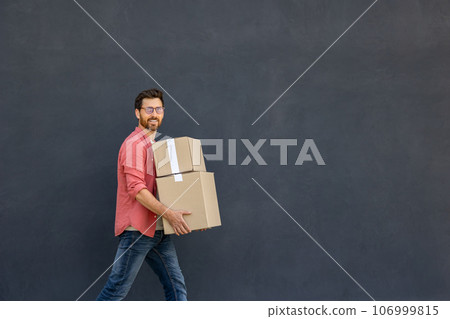 Dark-haired young man in eyeglasses carrying carton boxes Dark-haired young man in eyeglasses carrying carton boxes 106999815