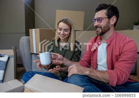 Dark-haired man holding a cup and thinking about how to pack it 106999855