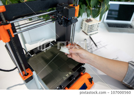 Man checking 3d printer, process of making things on 3d printer in laboratory. 107000560