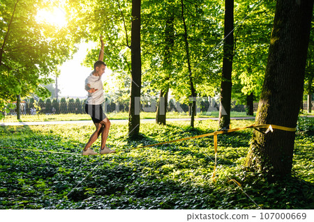 Man in sportswear doing slacklining in the forest Man in sportswear doing slacklining in the forest 107000669
