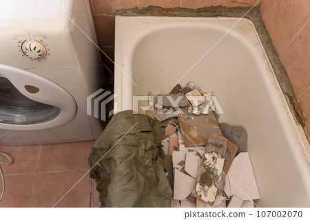 an old dirty shabby bathroom with fallen tiles. repair 107002070
