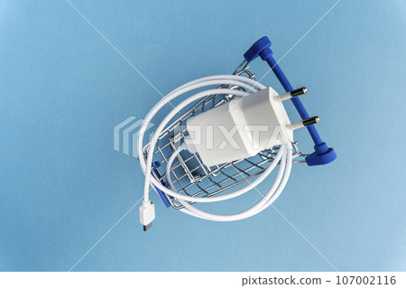 A phone charger in a supermarket cart on a blue background 107002116