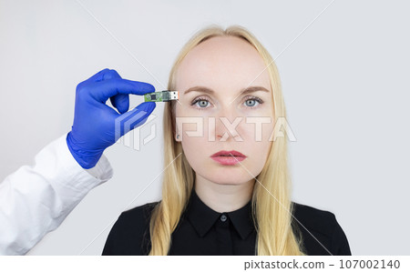 Usb memory stick in head. Flash drive to brain. Girl stands with memory card in her hand and wants to insert it into her body. Cybernetization and rapid learning technologies. Improving your own mind 107002140