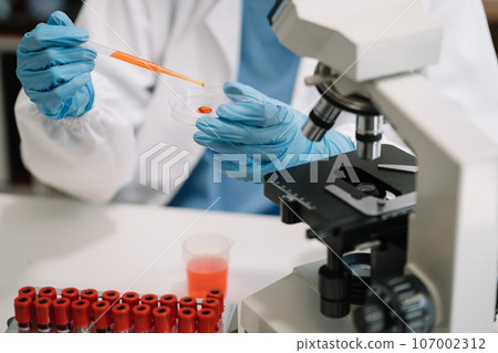 Science and medicine, scientist analyzing and dropping a sample into a glassware, experiments containing chemical liquid in laboratory on glassware, innovative and technology. 107002312