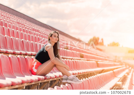 A female coach with dark hair stands on the red running track of the stadium 107002678