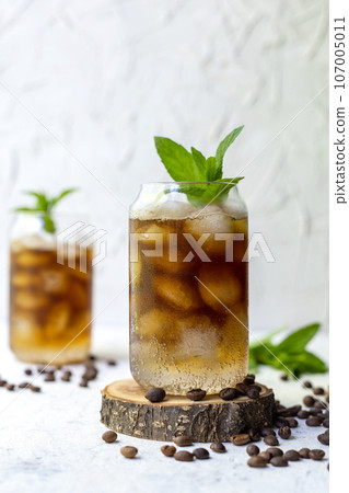 Cold summer cocktail with black coffee tonic mint and ice in glass on white background Cold summer cocktail with black coffee tonic mint and ice in glass on white background 107005011