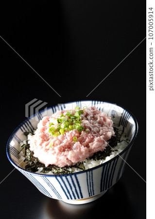 A bowl of shredded seaweed and green onions is photographed against a black background. 107005914