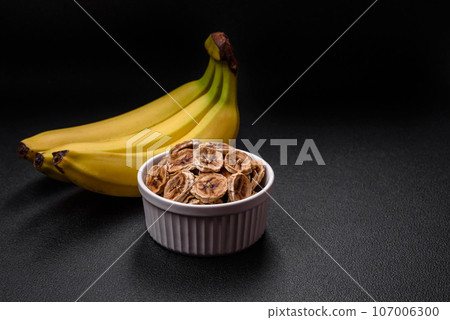 Round slices of sweet banana on a dark concrete background 107006300