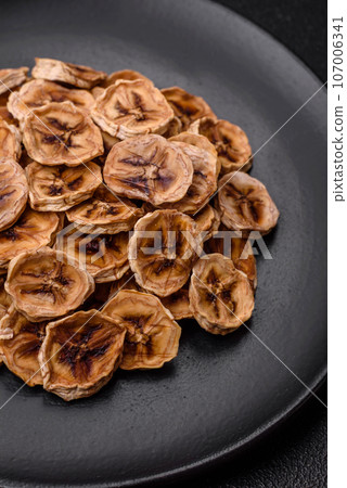 Round slices of sweet banana on a dark concrete background 107006341