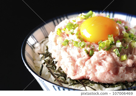 A bowl of shredded seaweed, egg yolk, and green onions is photographed against a black background. 107006469