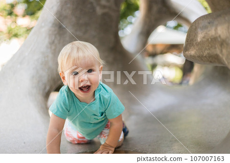 Child playing on outdoor playground. Toddler plays on school or kindergarten yard. Active kid on stone sculpured slide. Healthy summer activity for children. Little boy climbing outdoors Child playing on outdoor playground. Toddler plays on school or kindergarten yard. Active kid on stone sculpured slide. Healthy summer activity for children. Little boy climbing outdoors 107007163