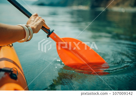 Kayak paddle sea vacation. Person paddles with orange paddle oar on kayak in sea. Leisure active lifestyle recreation activity rest tourism travel Kayak paddle sea vacation. Person paddles with orange paddle oar on kayak in sea. Leisure active lifestyle recreation activity rest tourism travel 107009142