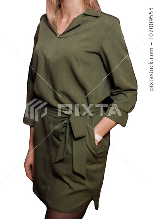 Thin girl posing with her hand in her pocket in a green fabric dress fashion and style of clothing on a white isolated background 107009553