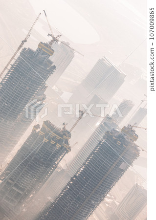 Huge skyscrappers construction site with cranes on top of buildings. Rapid urban and construction sector development or inflation of real estate bubble. 107009865