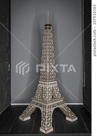 Eiffel Tower figurine made of simple material stands on a gray background of the room Eiffel Tower figurine made of simple material stands on a gray background of the room 107010163