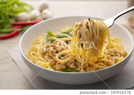 Spaghetti on the fork with stir fried minced chicken and basil,Spicy pasta Pad Kra Pao,Thai fusion food 107010176