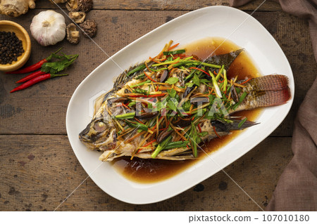 Steamed Tilapia Fish with Soy Sauce in white plate (Pla neung see ew).Top view 107010180