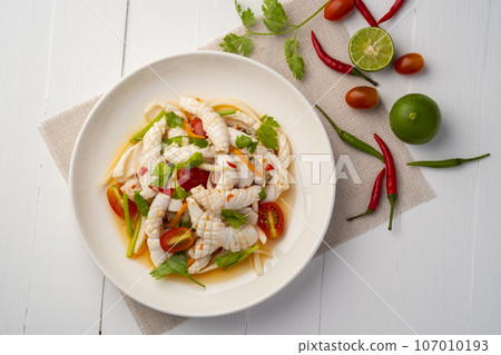 Thai Spicy Squid Salad,mixed squid with onion and tomato in chilli lime sauce in white plate.Thai food.Top view Thai Spicy Squid Salad,mixed squid with onion and tomato in chilli lime sauce in white plate.Thai food.Top view 107010193