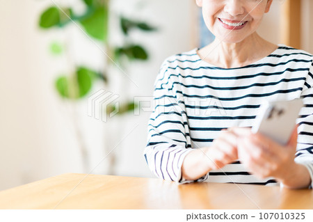 Senior woman operating a smartphone (parts model) 107010325