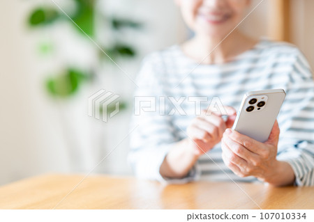 Senior woman operating a smartphone (parts model) 107010334