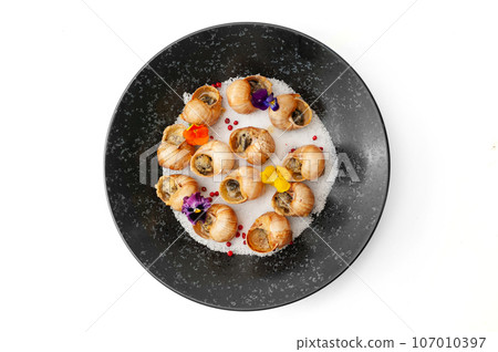 Cooked grape snails in shells on a black plate isolated 107010397
