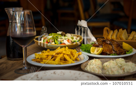 traditional albanian food. restaurant dinner. baked lamb meat with salad, tzatziki and potatoes traditional albanian food. restaurant dinner. baked lamb meat with salad, tzatziki and potatoes 107010551