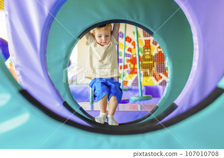 Cute little boy crawling and playing on colorful playground at amusement park Cute little boy crawling and playing on colorful playground at amusement park 107010708
