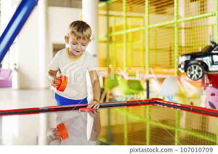 A cute kids playing with a puck in an air hockey in an amusement park A cute kids playing with a puck in an air hockey in an amusement park 107010709