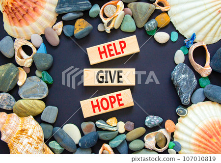 Help give hope symbol. Concept word Help give hope on beautiful wooden block. Sea shell stone. Beautiful black table black background. Business motivational help give hope concept. Copy space. Help give hope symbol. Concept word Help give hope on beautiful wooden block. Sea shell stone. Beautiful black table black background. Business motivational help give hope concept. Copy space. 107010819
