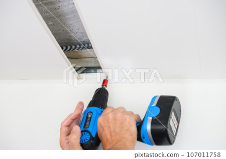 Worker assemble a suspended ceiling and fixing panel with an screwdriver. Worker assemble a suspended ceiling and fixing panel with an screwdriver. 107011758