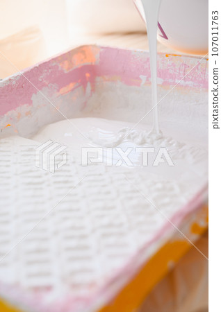 A white paint is poured into the tray. 107011763