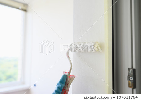 Worker painting on surface wall with paint roller brush. Worker painting on surface wall with paint roller brush. 107011764