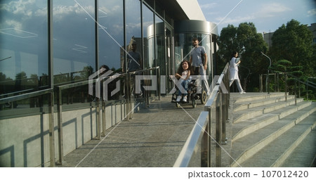 Male nurse opens door to female patient in wheelchair 107012420