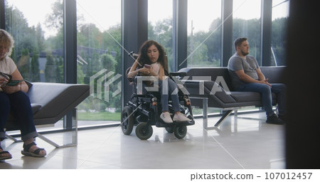Woman with disability waits for appointment with doctor in clinic lobby 107012457