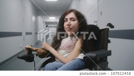 Woman with spinal muscular atrophy looks at camera 107012458