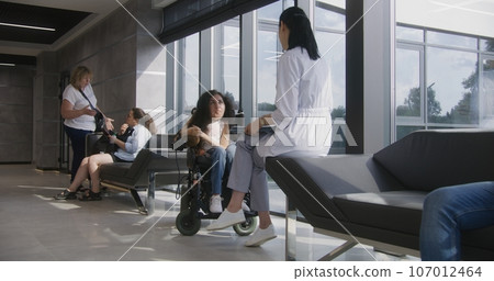 Physician consults patient with spinal muscular atrophy in clinic lobby 107012464