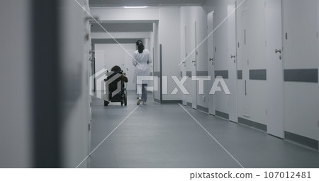 Female doctor walks down the clinic hallway, consults woman with disability 107012481