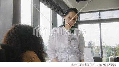 Physician talks to woman with disability in hospital or clinic lobby 107012505