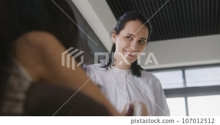 Female doctor consults patient with physical disability in clinic lobby 107012512