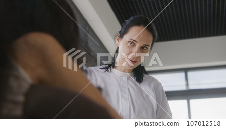 Female doctor consults patient with physical disability in clinic lobby 107012518
