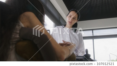Physician talks to woman with disability in hospital or clinic lobby 107012521