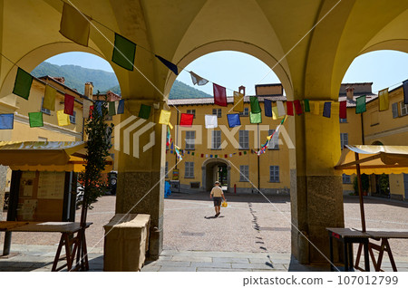Courtyard alley in medieval Italian town, decorated with colorful flags for a festival. Travel and tourism concept Courtyard alley in medieval Italian town, decorated with colorful flags for a festival. Travel and tourism concept 107012799